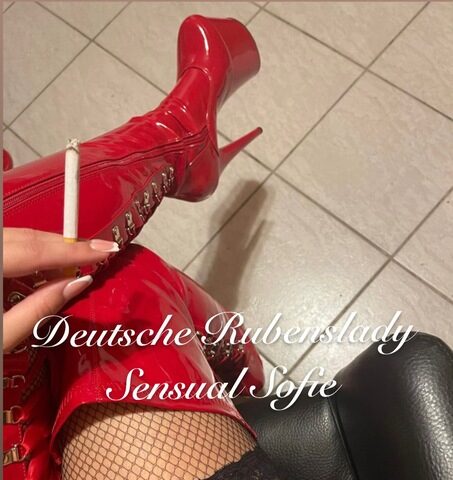 Eine Person in roten Lackstiefeln und Spitzenstrümpfen hält eine Zigarette in der Hand. Der Text „Deutsche Rubenslady Sensual Sofie“ ist über das Bild gelegt.